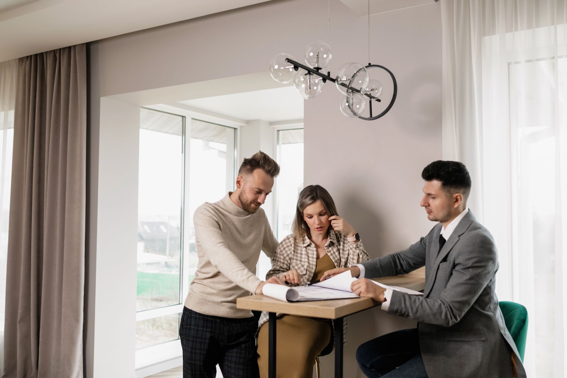 A couple consults with a real estate agent reviewing property documents